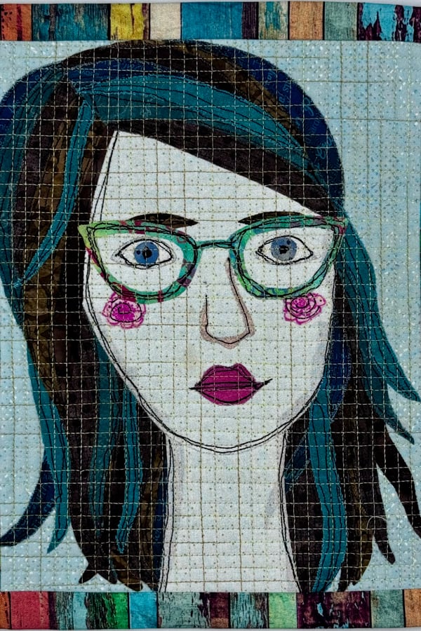 Mandy Manno, Fabric Collage Instructor, shown as her own quilted fabric self-portrait